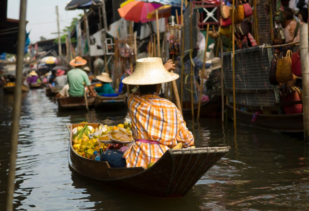 Lokale belevenis tijdens je individuele reis Thailand – vaar tussen kleurrijke kraampjes op een authentieke drijvende markt.