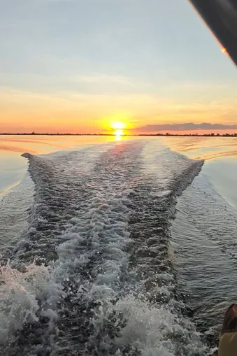 Achterkant van een boot op de Zambezi-rivier bij zonsondergang, met gouden licht dat schittert op het water.