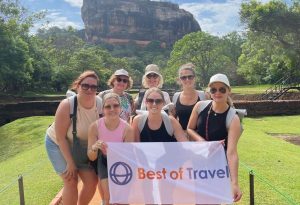 Groepsfoto van Best of Travel-team voor de iconische rots van Sigiriya in Sri Lanka, met een banner van Best of Travel op de voorgrond."
