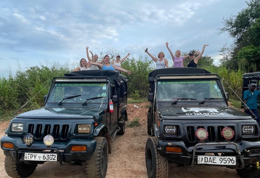 Groepsleden juichen enthousiast bovenop safari-jeeps in de natuur van Sri Lanka, klaar voor een avontuurlijke rit."