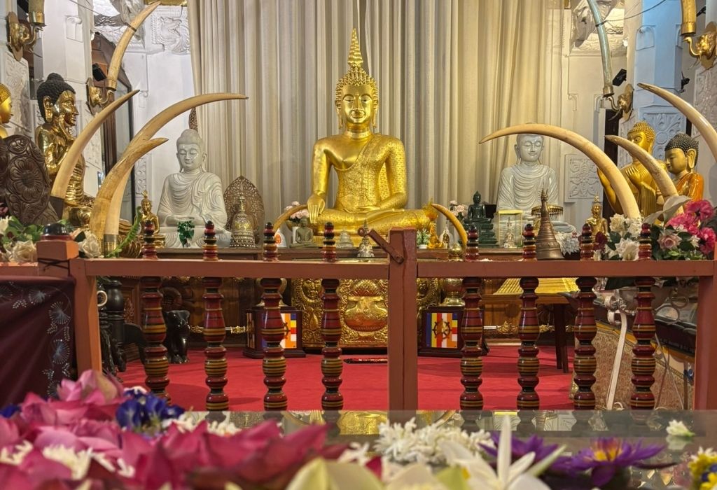 Gouden en witte Boeddhabeelden in een rijk versierde tempel in Sri Lanka, omringd door bloemen en olifantenslagtanden."