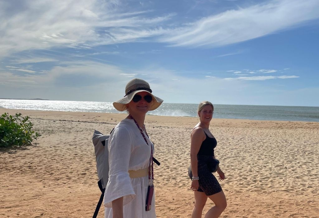 Twee vrouwen wandelen ontspannen over een zonovergoten strand aan de zuidkust van Sri Lanka met uitzicht op de Indische Oceaan.
