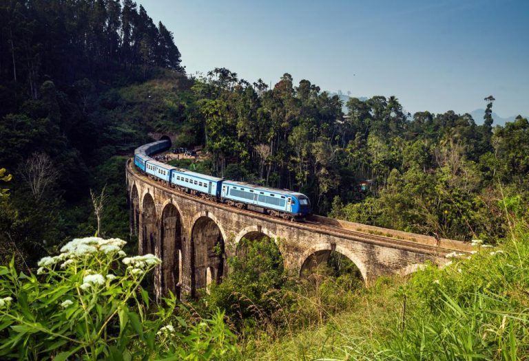 Blauwe trein rijdt over de iconische Nine Arch Bridge midden in de groene heuvels van Ella, Sri Lanka